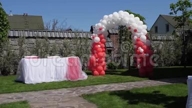 婚礼拱门由红白气球制成，婚礼仪式，绿色草坪。